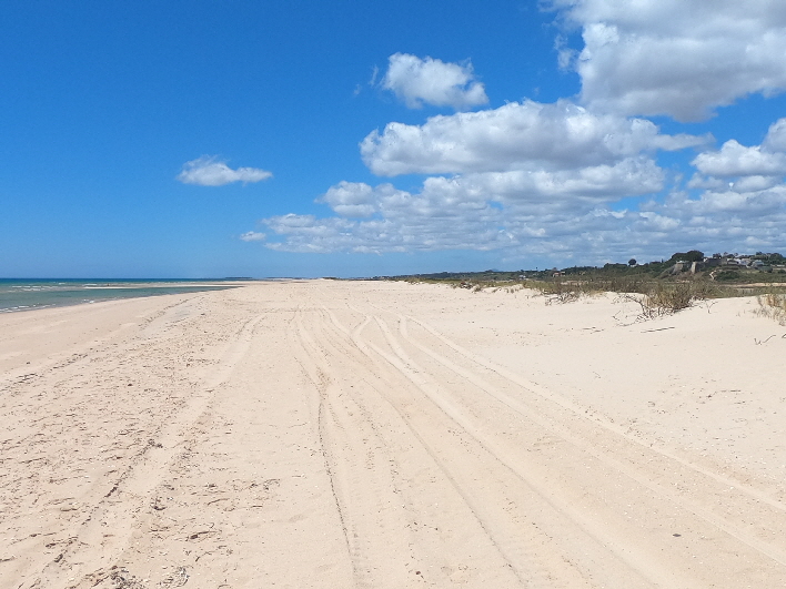 langer und breiter Strand mit "Küstenwetter" (Wolken über dem wärmeren Land)